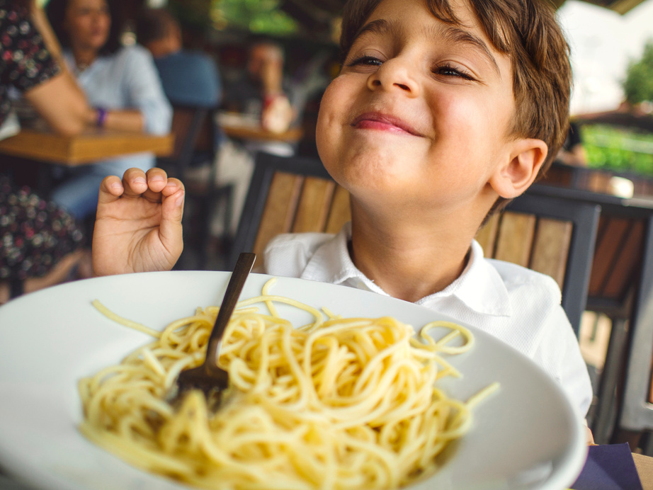 Child having fun eating pasta.